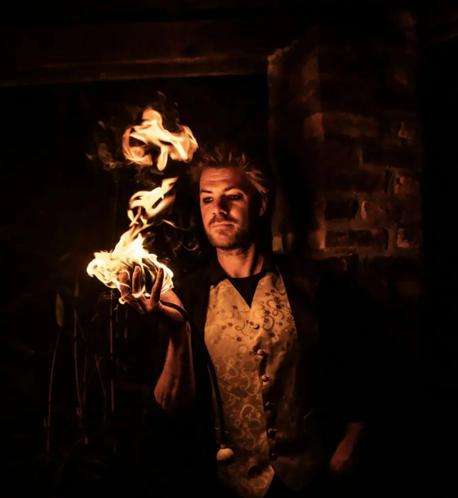Jongleur de feu raffiné tenant une boule de feu à main nue, offrant une performance visuelle hypnotique.